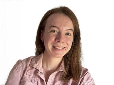 Smiling woman with long brown hair in a pink shirt.
