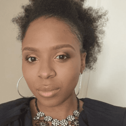 Headshot of a young Black woman with curly hair, hoop earrings, and a statement necklace.