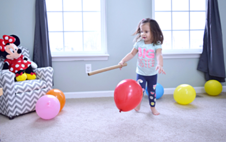 A toddler playing with balloons