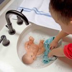 A child giving a doll a bath