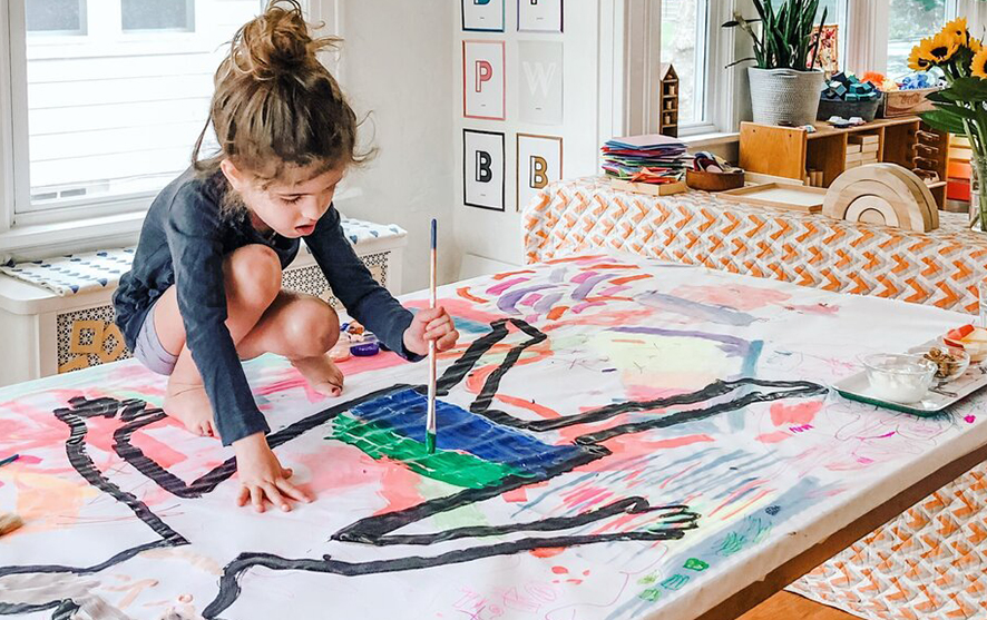 A girl painting an outline of a person on a canvas - body tracing