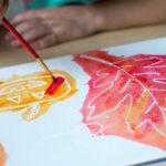 A white crayon drawing of a leaf and pumpkin