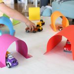 A child playing with car tunnels made out of paper