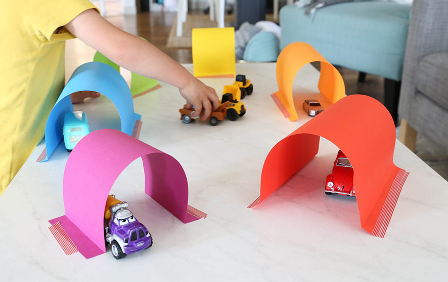 A child playing with car tunnels made out of paper