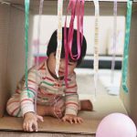 A baby playing in a cardboard box