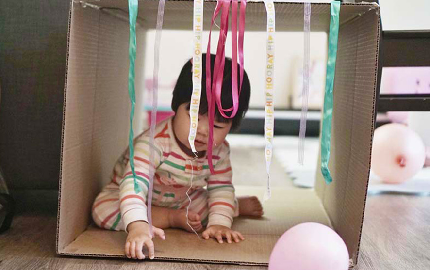 A baby playing in a cardboard box