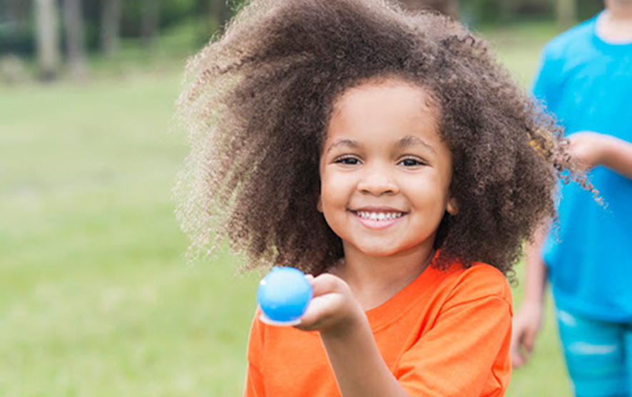 A girl holding an egg in a spoon for an egg and spoon race