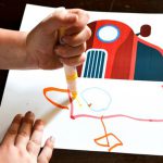 A child drawing a half drawing of a car with a marker