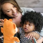 A woman holding her daughter while she reaches for a toy