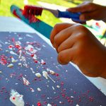 A child painting with a toothbrush