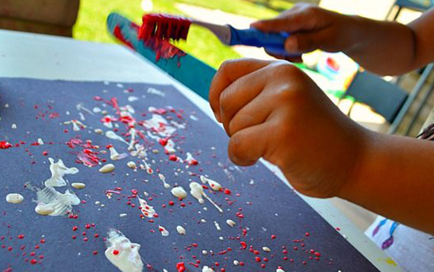 A child painting with a toothbrush