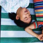 Two children laying on the ground and looking at clouds