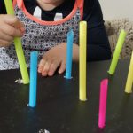 A child playing the push and pull game with straws and cardboard box