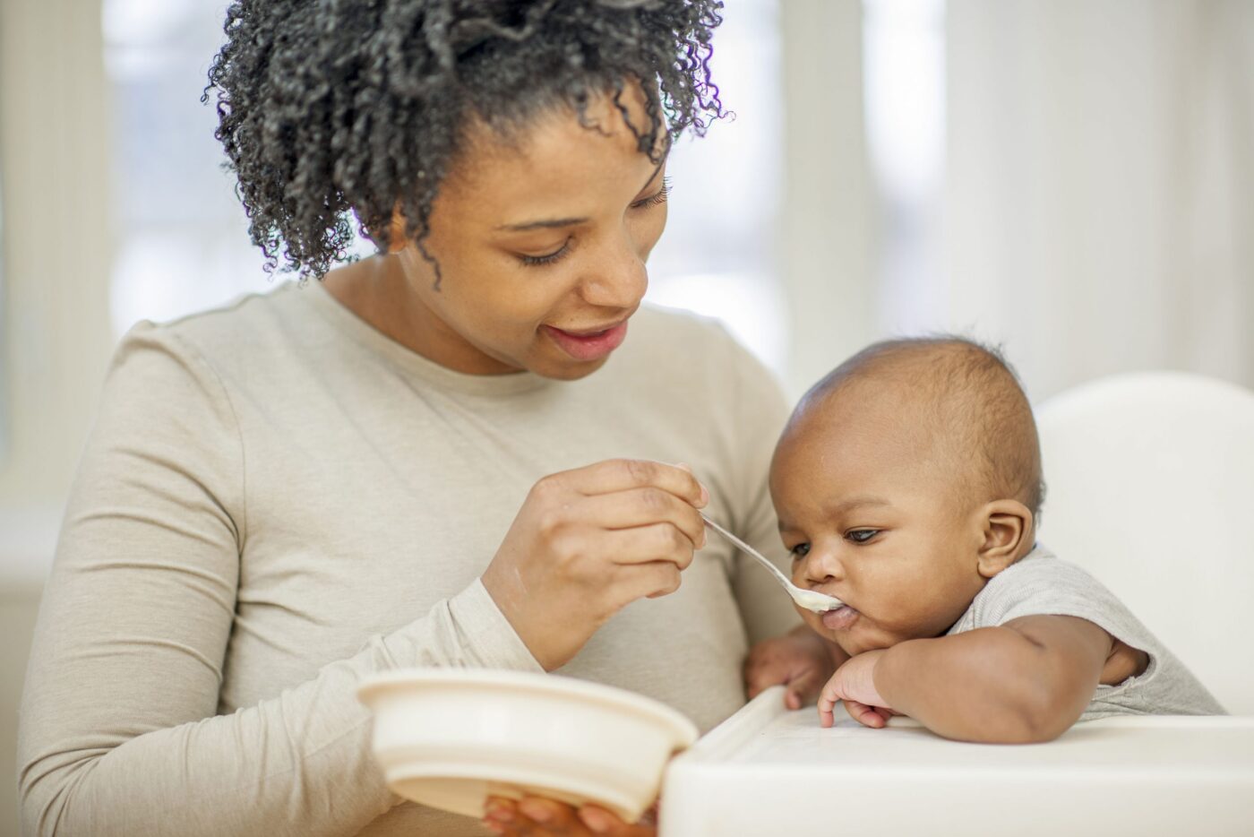 A mom feeding a small baby by spoon