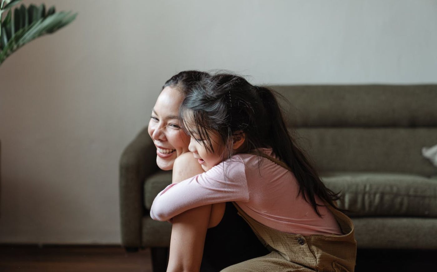 A daughter hugging her mom while she does yoga