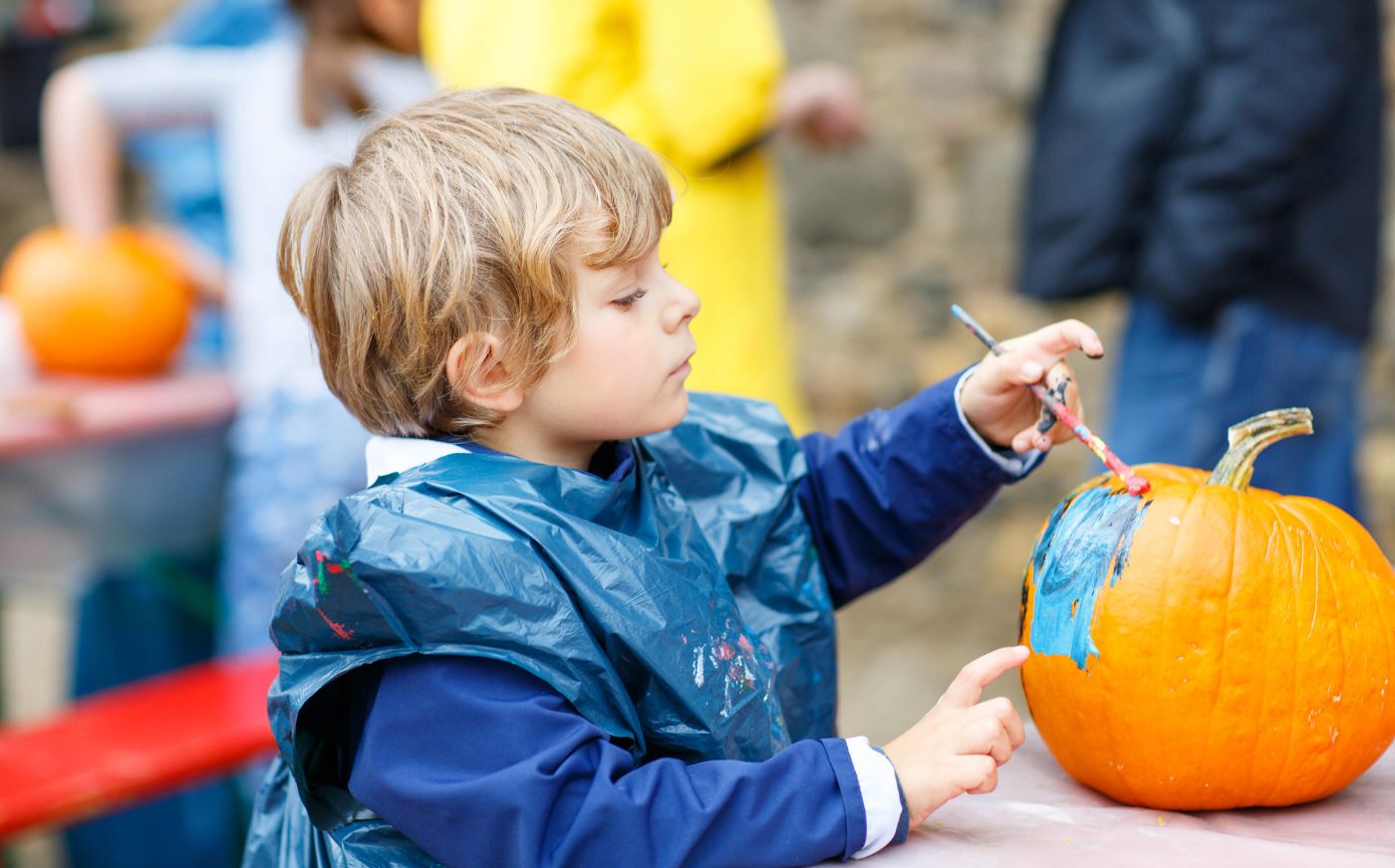 A little boy painting a pumpkin