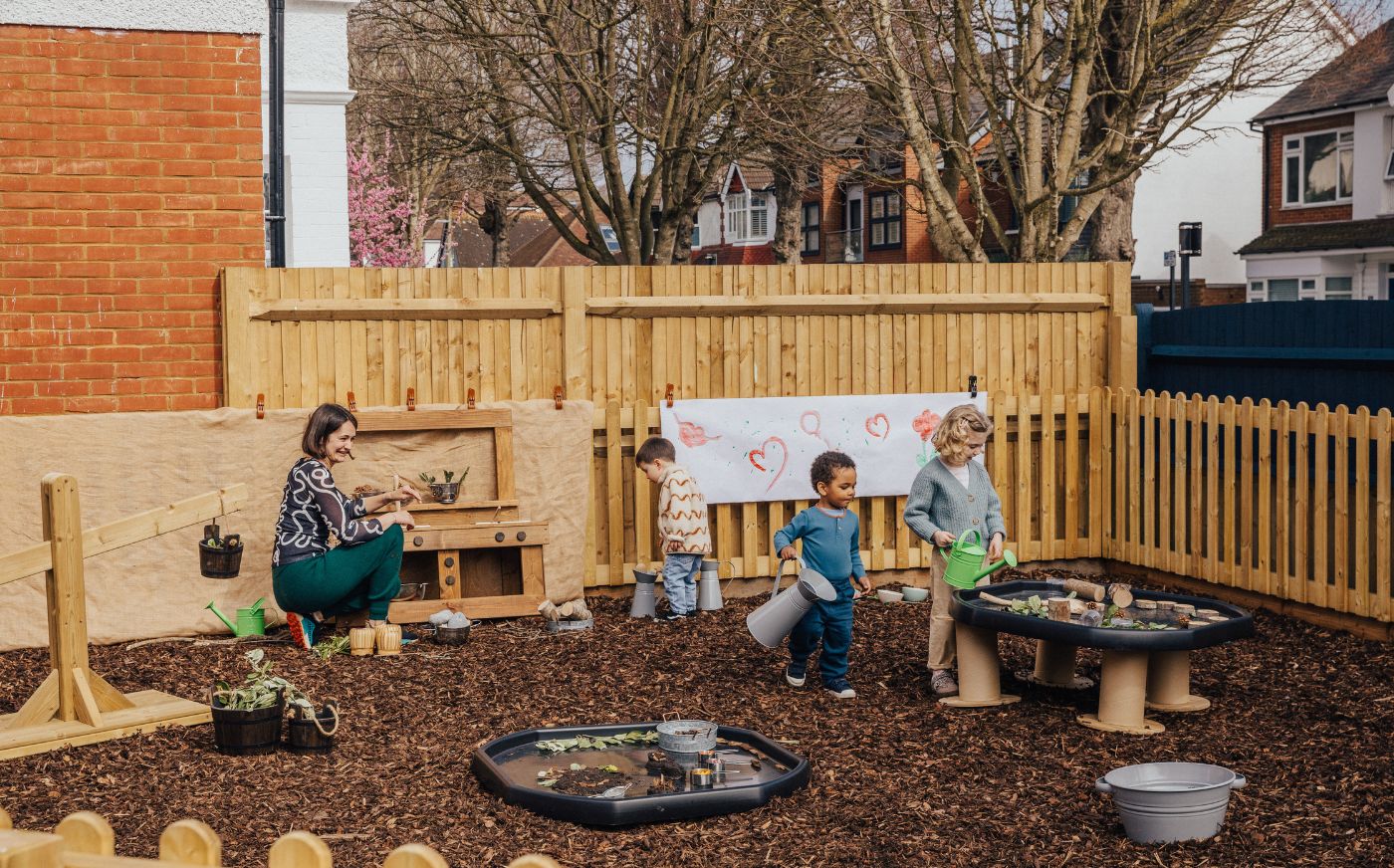 An educator watching children enjoying outdoor play learning